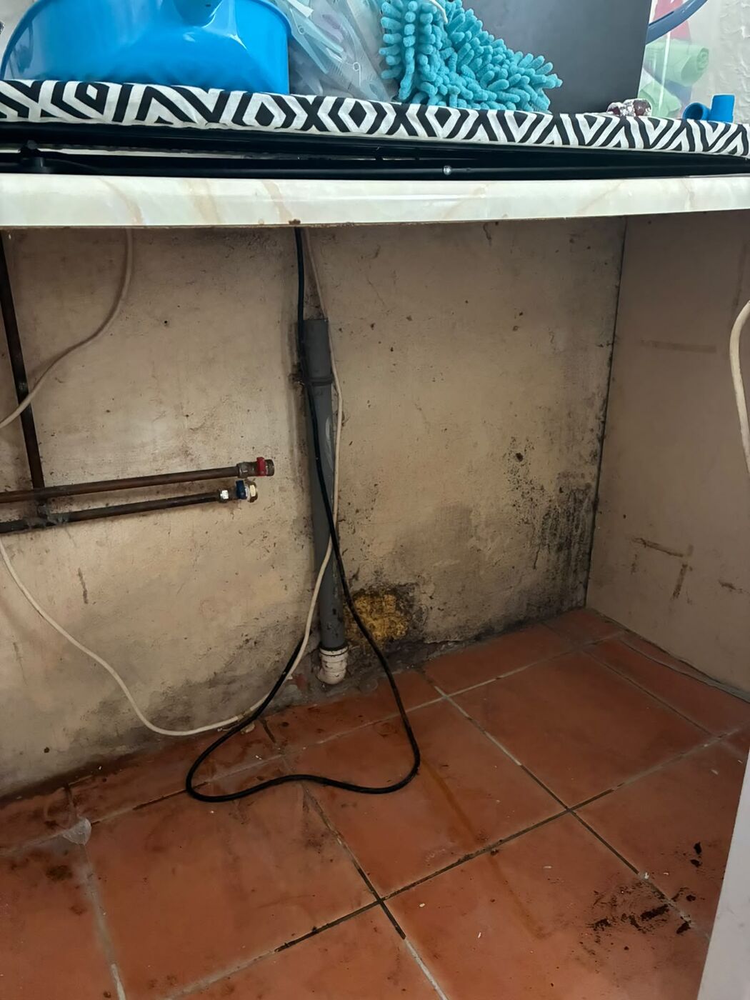 Bare utility wall showing appliance supply pipe work and waste connection after removal
