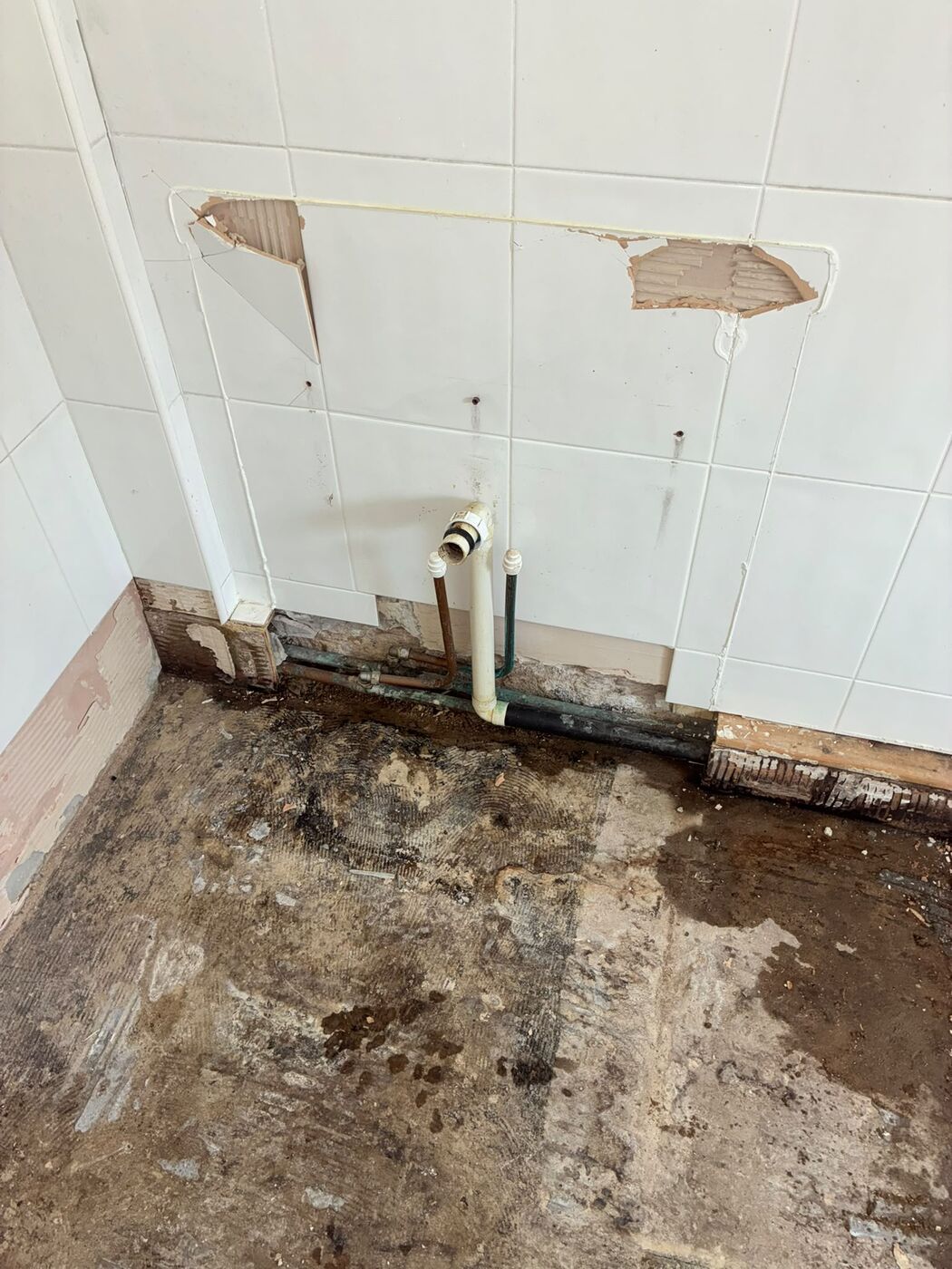 Stripped bathroom wall with an access opening and exposed pipe work