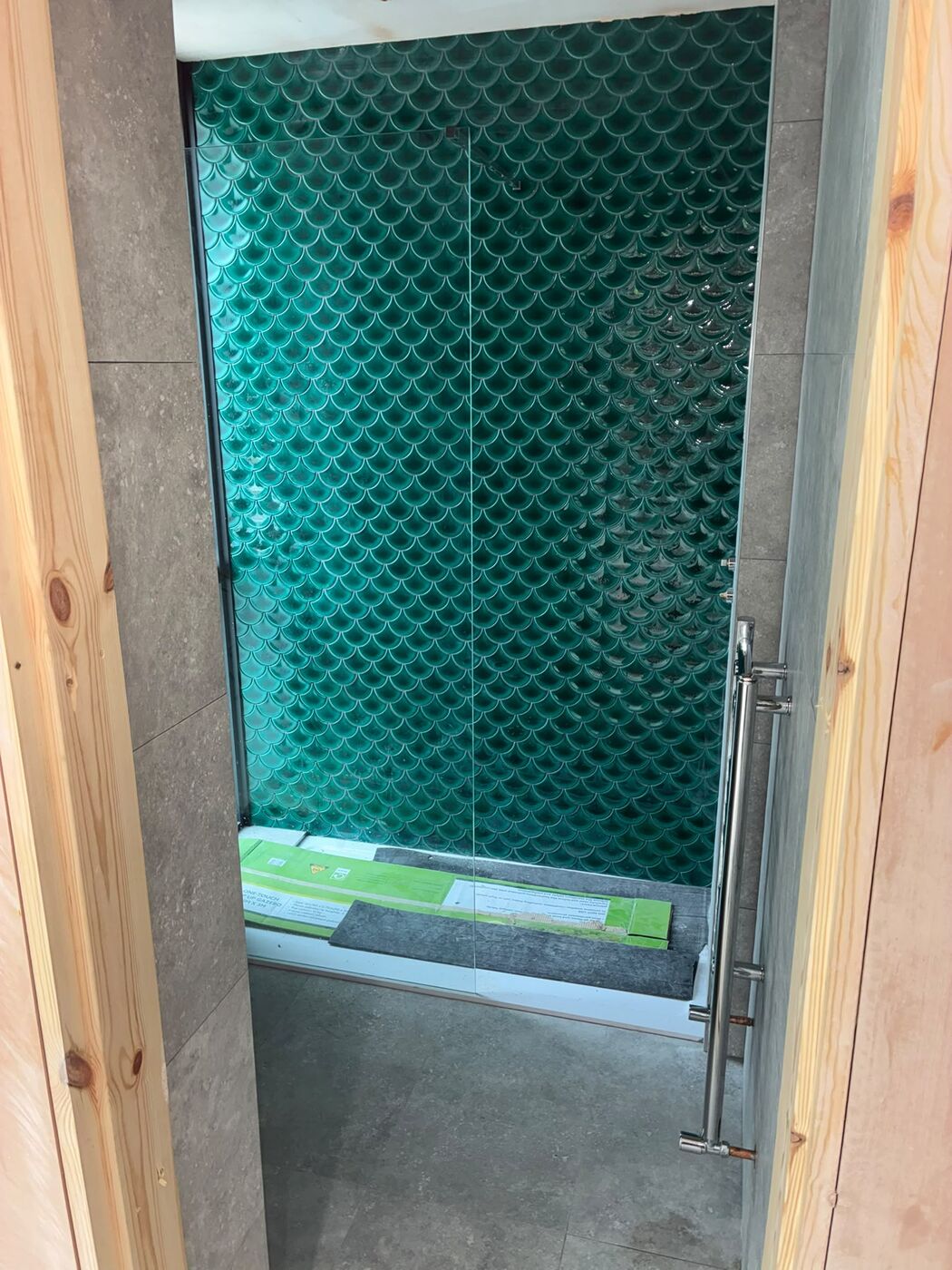 Tiled shower enclosure with green feature tiles and a glass screen fitted