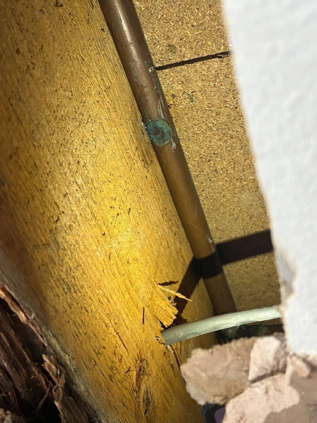 Copper pipe run exposed behind a wall board while tracing a water leak