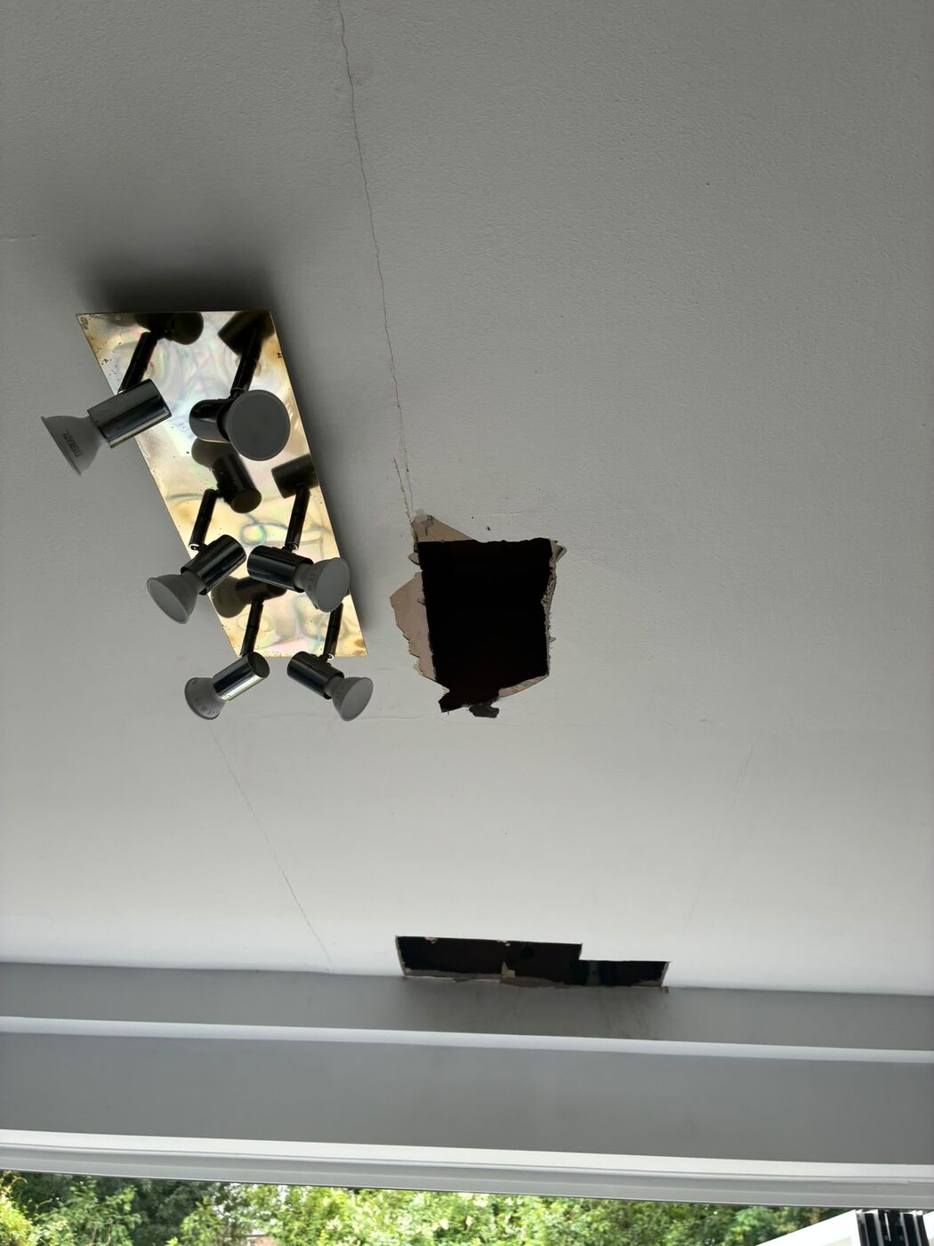 Repaired pipe joints with fittings visible through two neat access openings in a ceiling